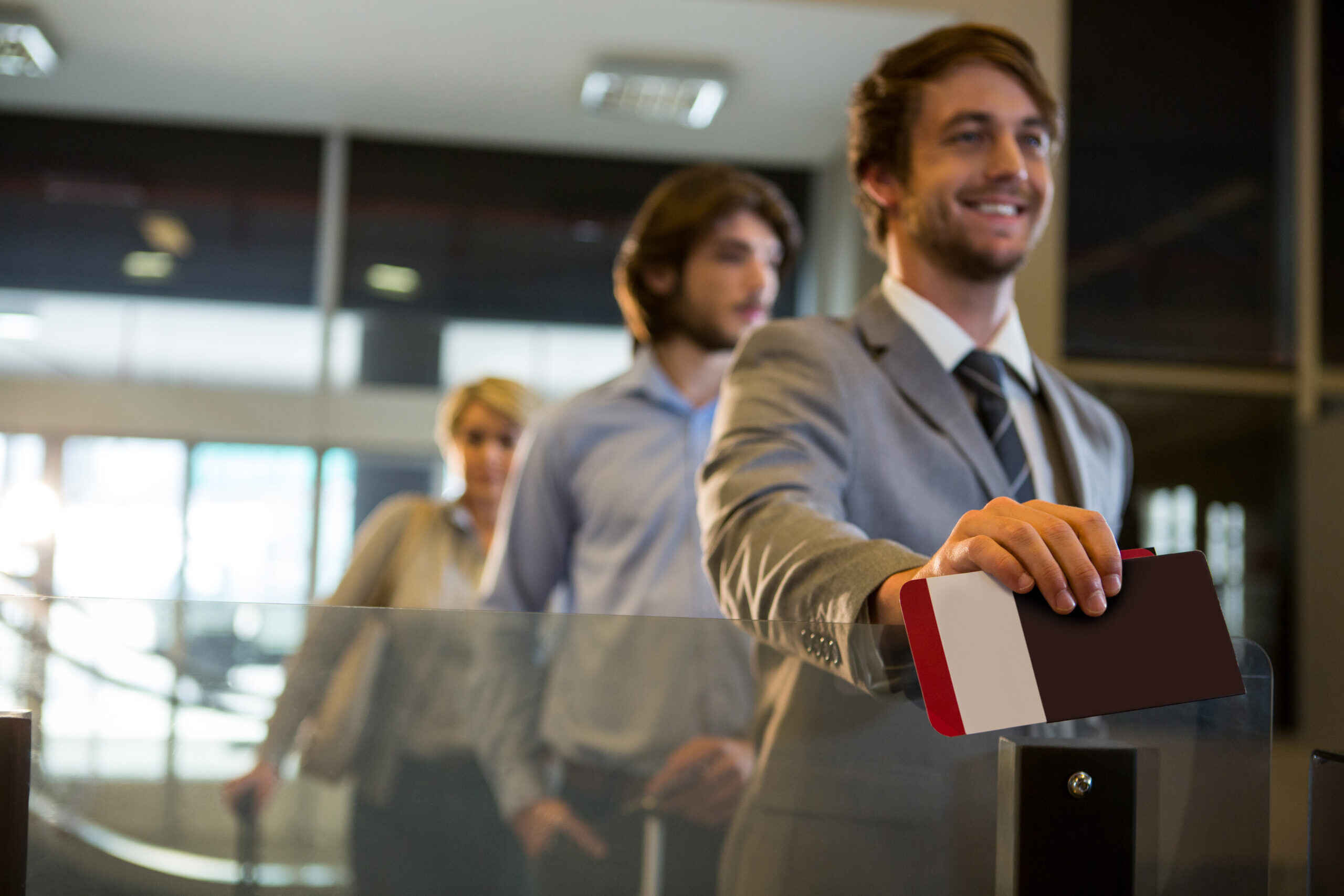 Businessman standing with boarding pass at check-in counter in airport